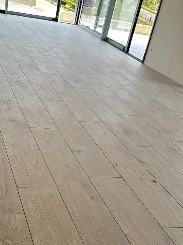 Carrelage effet bois en lames, pose décalée, dans une pièce entourée de baies vitrées