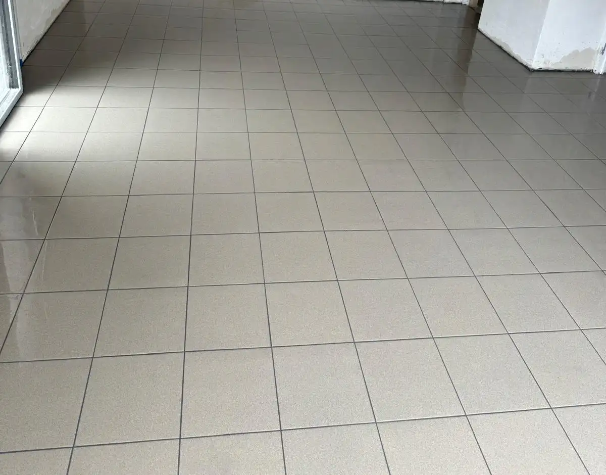 Sol de garage carrelé en beige, carreaux carrés alignés et joints gris