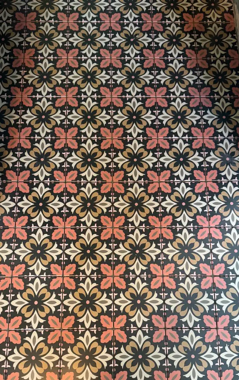 Sol en carrelage à motifs effet carreaux de ciment, tons corail, ocre et noir, vu de dessus