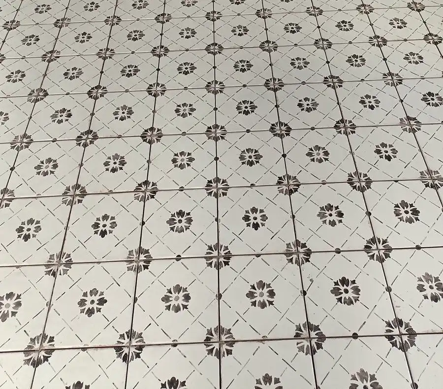 Carrelage à motifs floraux noirs sur fond blanc posé dans un couloir